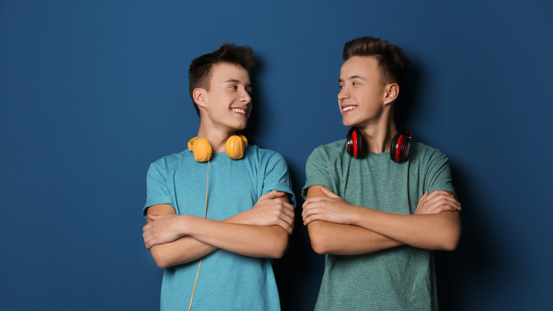 Nastoletni bracia bliźniacy ze słuchawkami na kolorowym tle